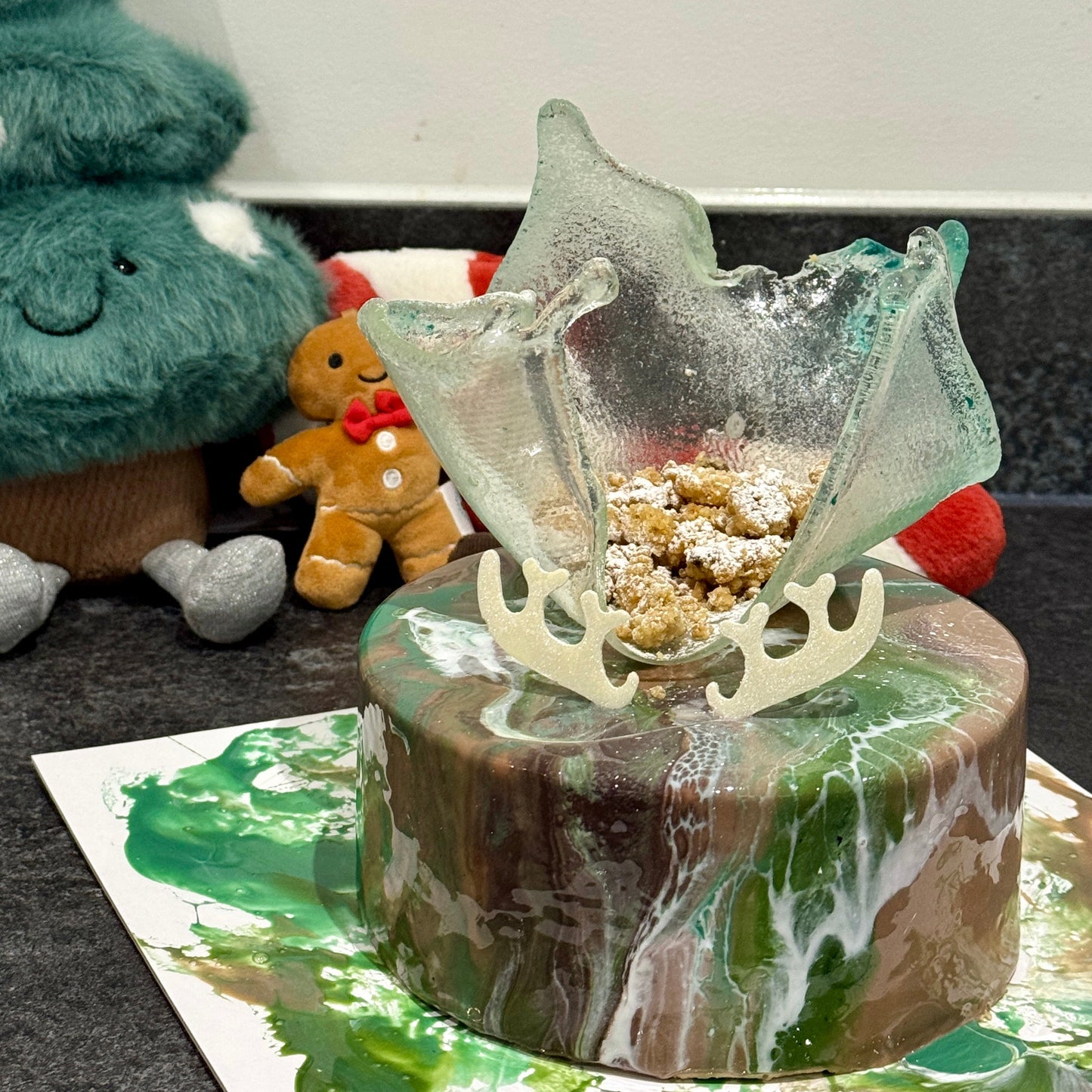 Decorative cake with reindeer antlers and a glass top on a countertop.