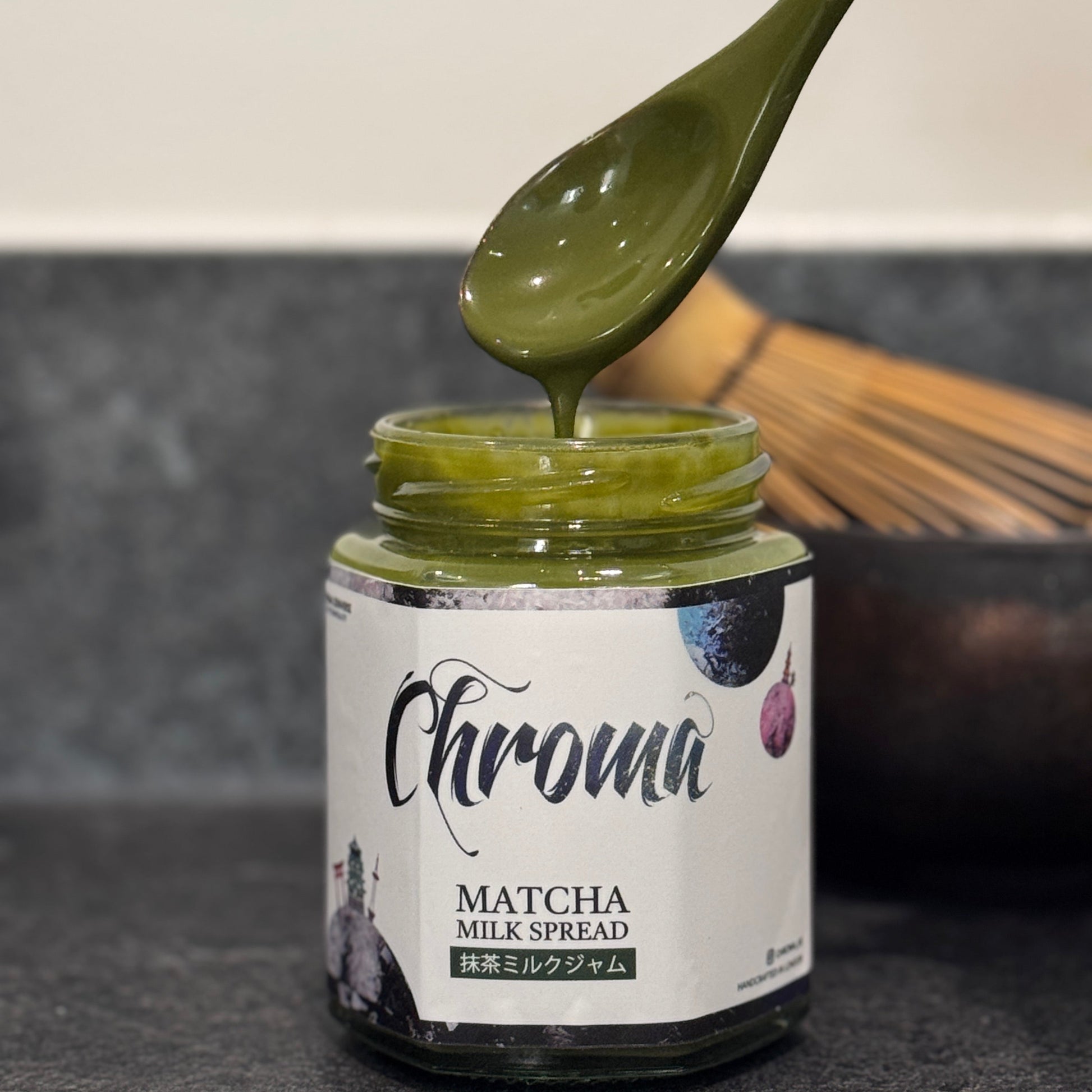 Jar of Chroma Matcha Milk Spread with a spoon lifting some spread.